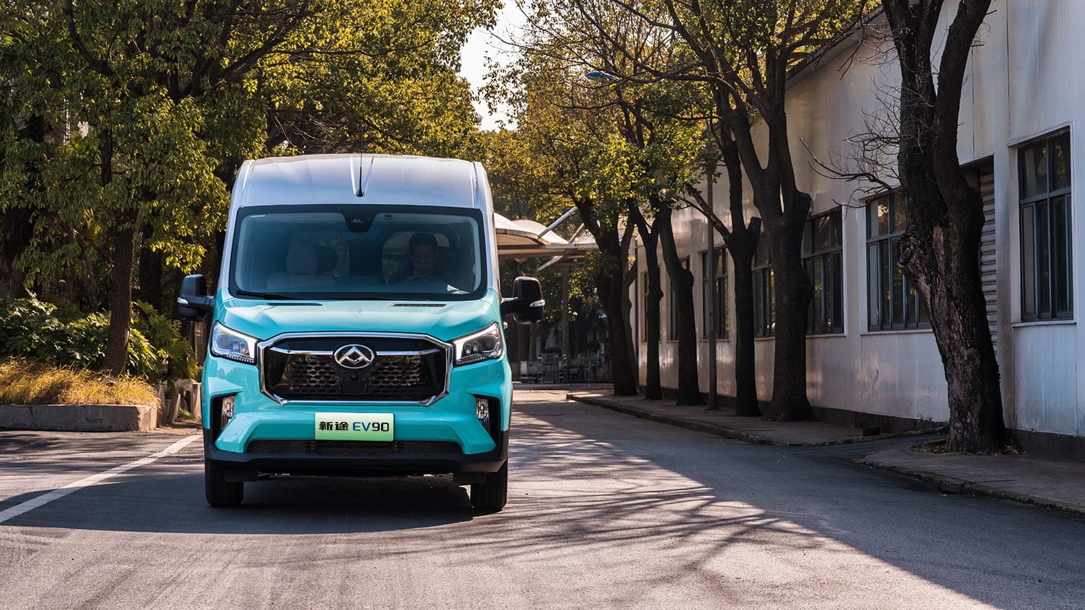 2026 MAXUS EV90 — Large Electric Van and 9–15 Seat Minibus for export, front view in a tree-lined street